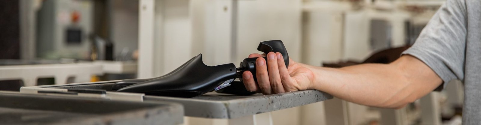 A shoe maker holding a shoe last inside the manufacturing factory